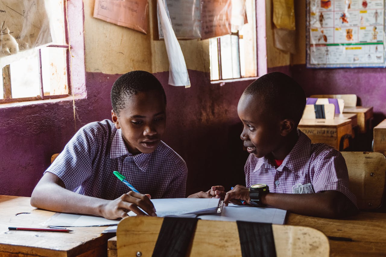 Two boys collaborating on schoolwork in a classroom setting with natural light.