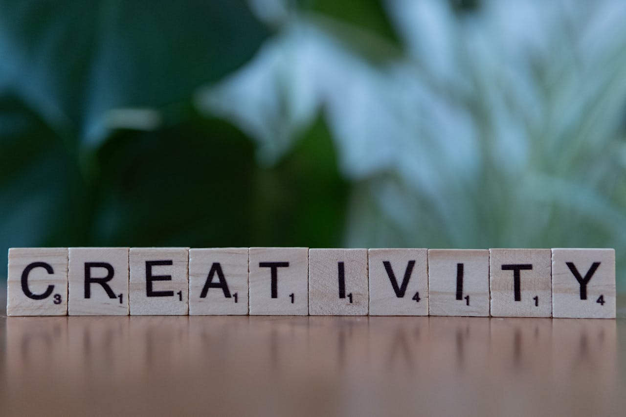 Scrabble tiles spelling 'CREATIVITY' with a blurred green background.