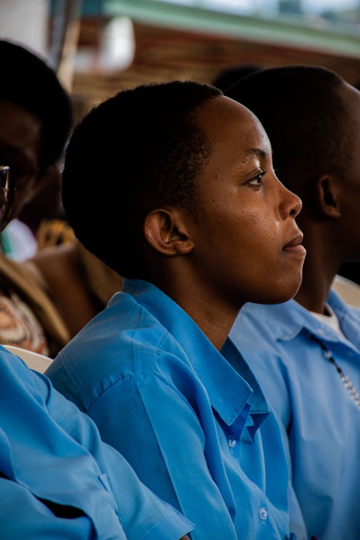 A group of students in blue uniforms attentively listening during a class session.